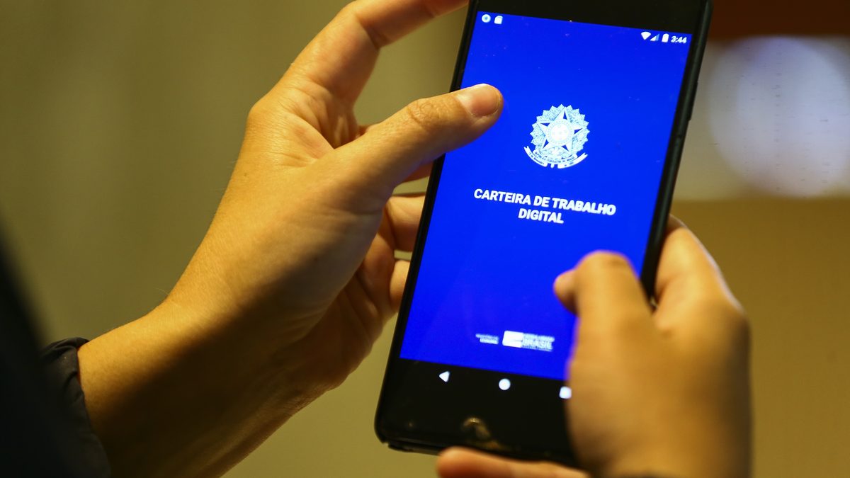Mãos seguram um celular com a tela de abertura do aplicativo Carteira de Trabalho Digital, em foto de arquivo da Agência Brasil