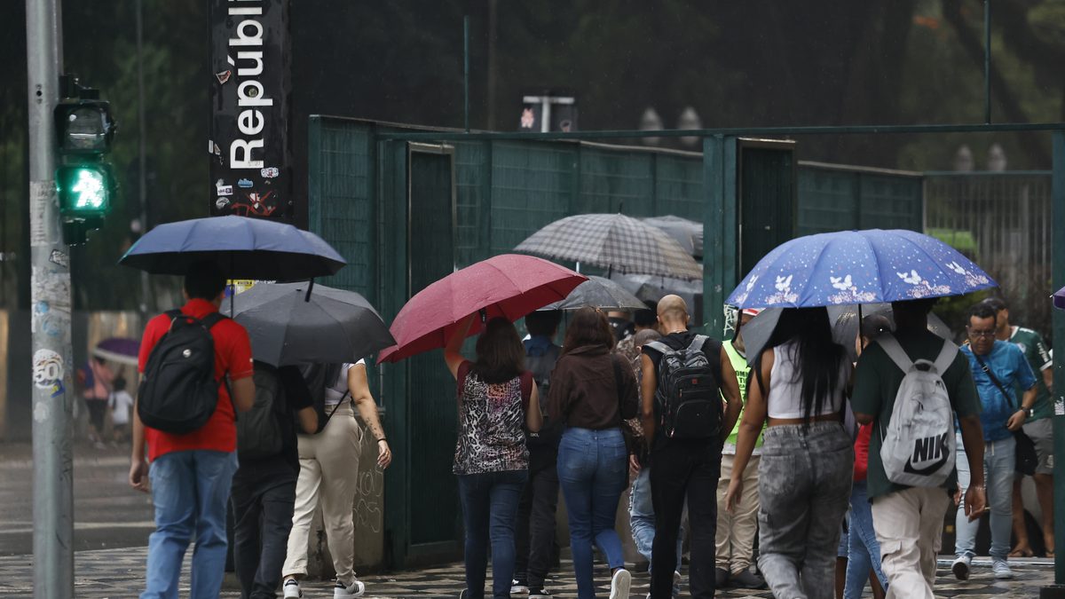 Pessoas com guarda-chuvas caminham na chuva em frente à estação República, em São Paulo