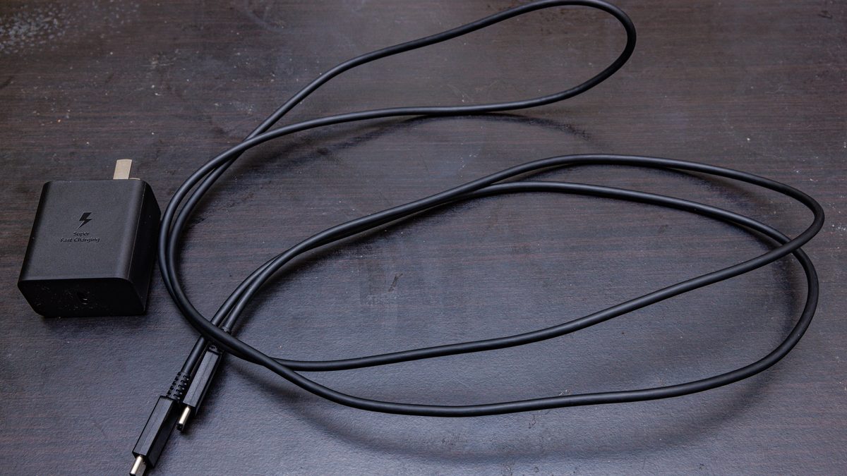 Carregador de parede Samsung de 45 W, preto, e um cabo USB-C para USB-C solto sobre a mesa