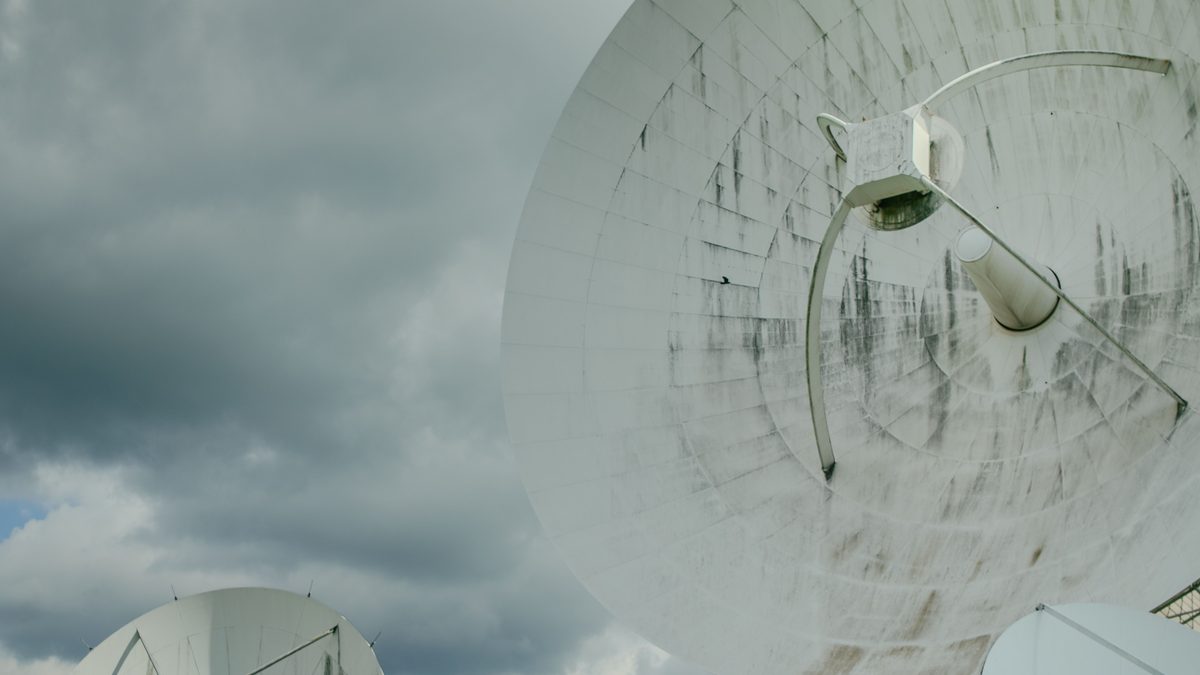 Antenas parabólicas brancas de uma estação de comunicação por satélite sob céu nublado