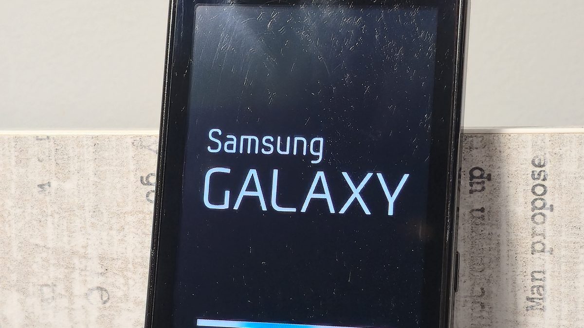 Celular antigo de tela preta mostrando a tela de inicialização, com o nome da marca e uma barra de carregamento