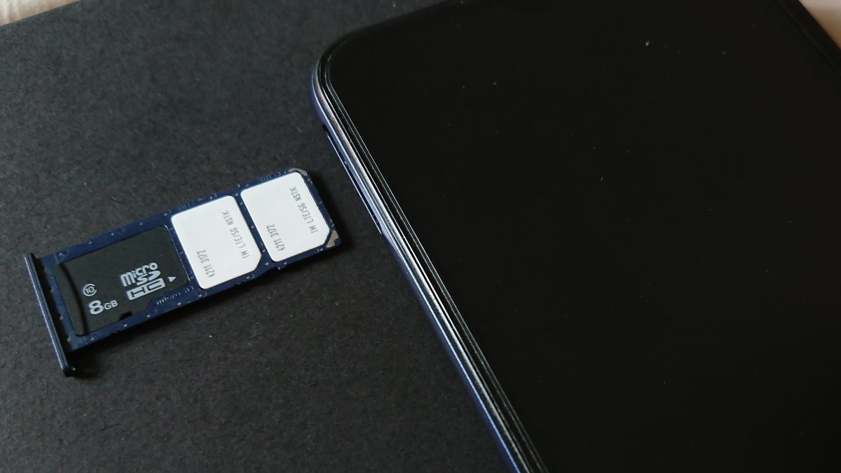 Bandeja de chip com dois chips e um cartão de memória retirada de um celular, sobre uma mesa escura