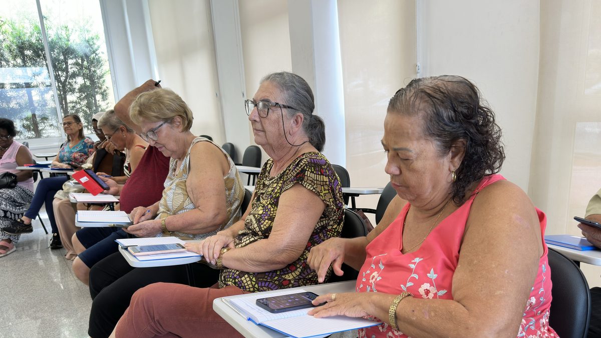 Mulheres idosas sentadas em carteiras seguram o celular durante curso de tecnologia para idosos em São José do Rio Preto