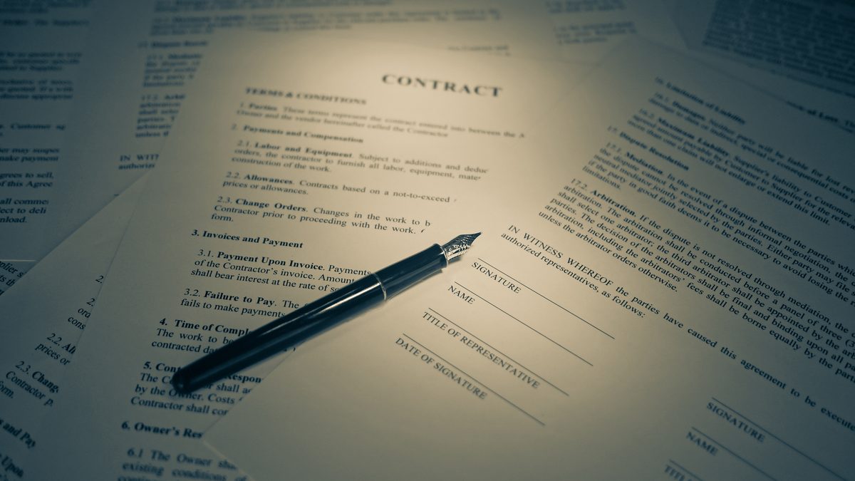 Caneta tinteiro sobre folhas de contrato com campos de assinatura em branco