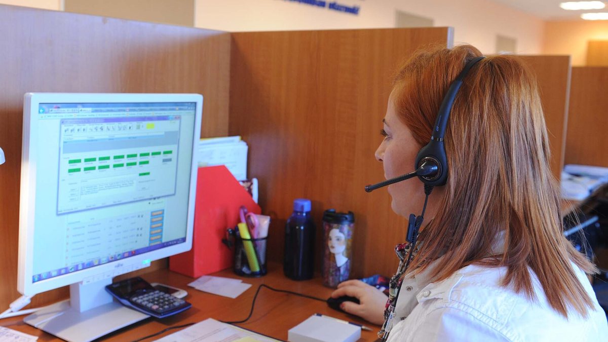 Atendente com fone de ouvido trabalha numa central de atendimento telefônico