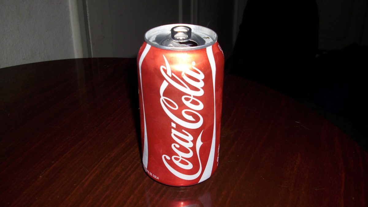 Lata de Coca-Cola vendida no Brasil sobre uma mesa de madeira