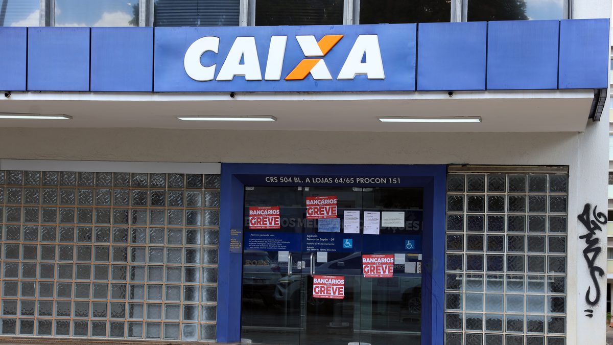 Fachada de agência da Caixa em Brasília com cartazes de Bancários em greve colados na porta de vidro