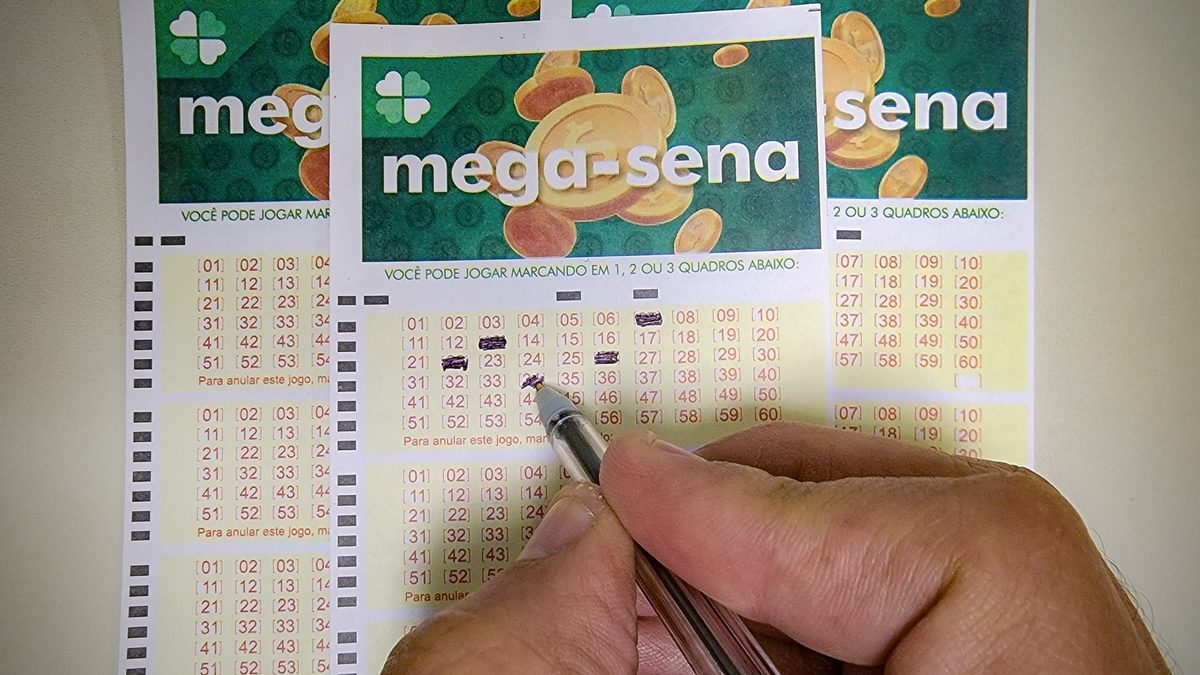 Mão com caneta marca números em volantes da Mega-Sena em uma casa lotérica da Caixa, em foto de arquivo de 2023