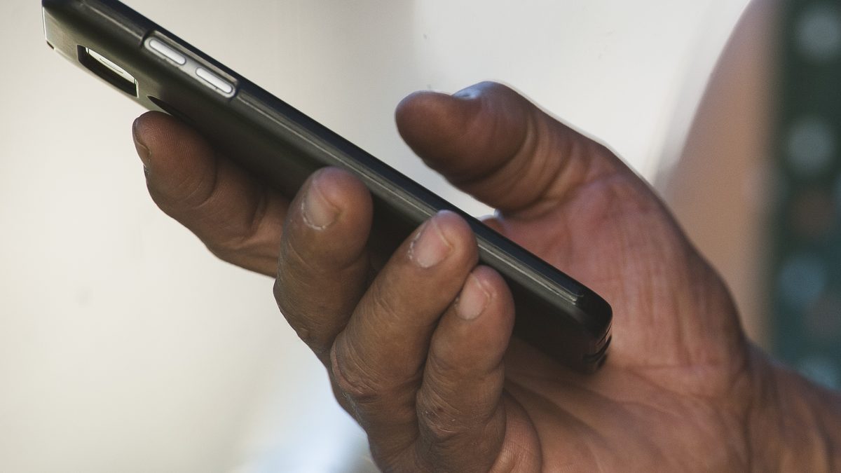 Mão segurando um smartphone preto, visto de lado