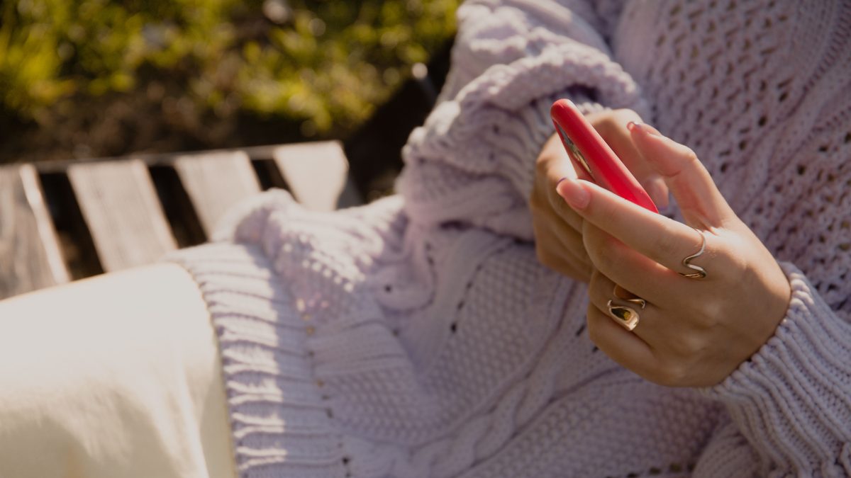 Mulher segura um celular de capa vermelha