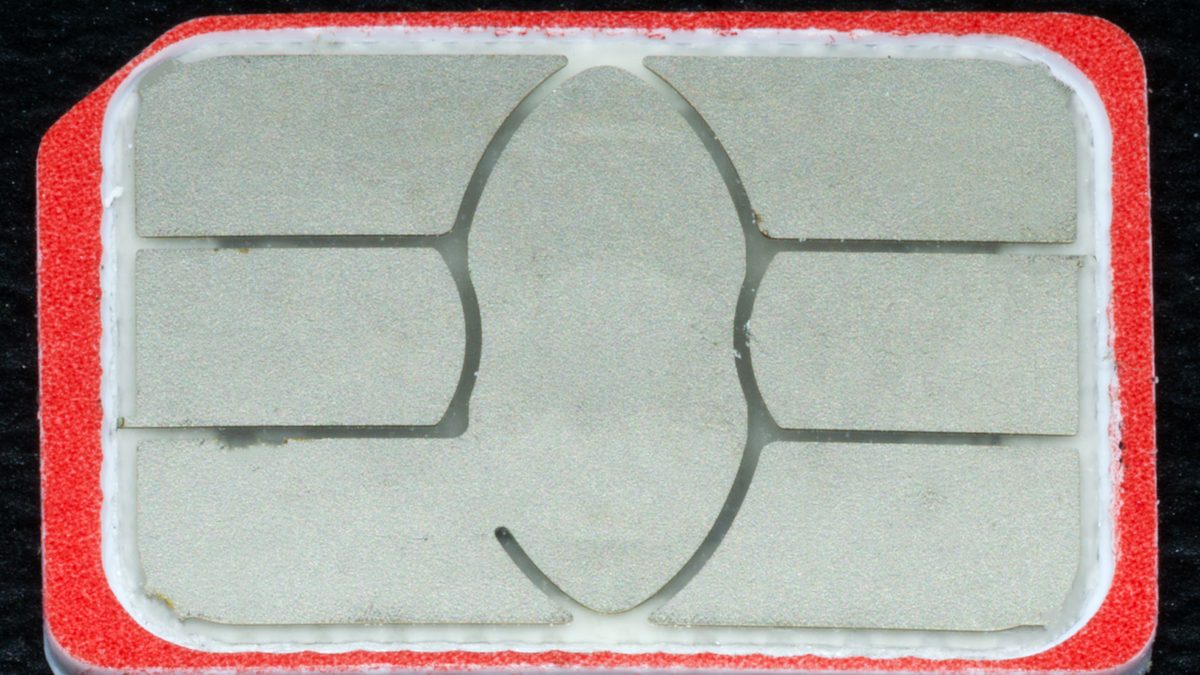 Chip nano SIM de celular visto de perto, com os contatos metálicos à mostra