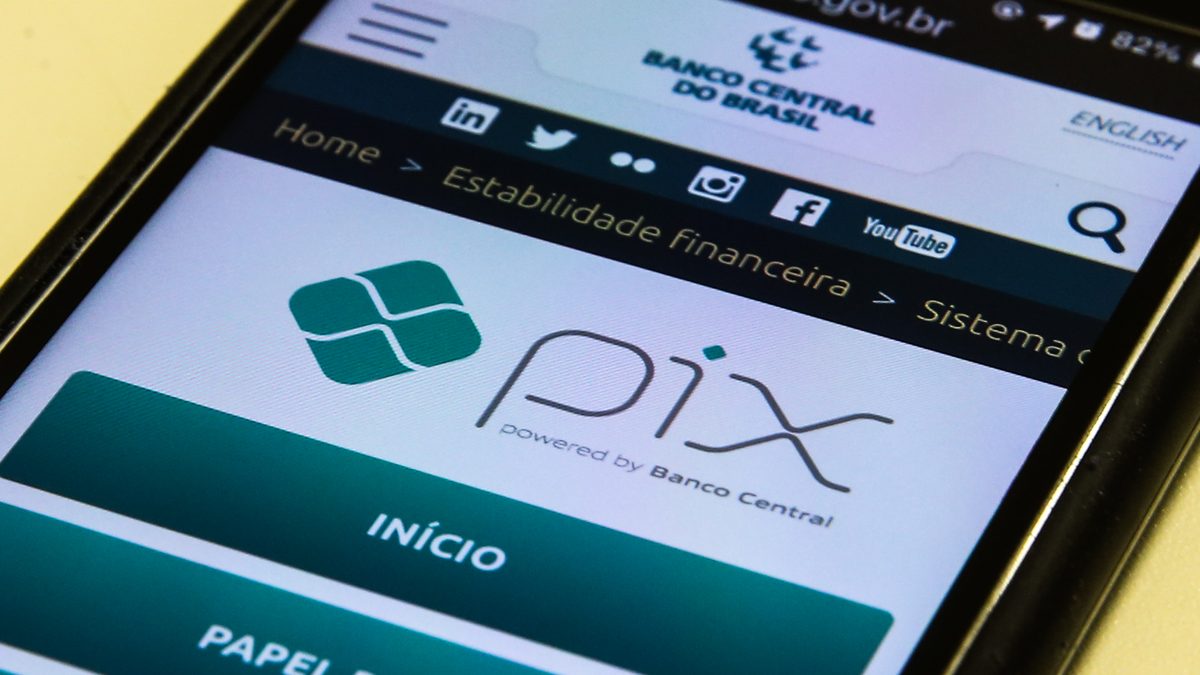 Celular com a página do Pix no site do Banco Central aberta na tela, com o logotipo do Pix e os botões Início e Papel do BC