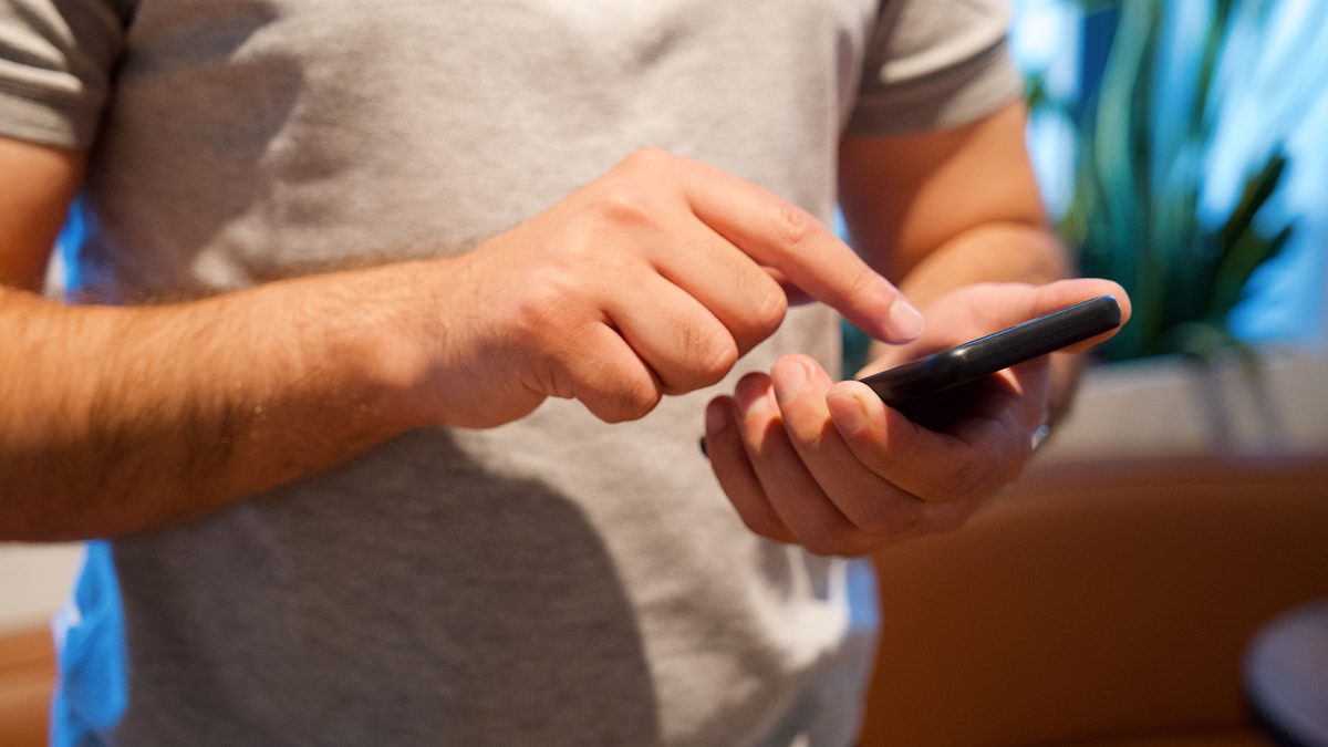 Homem usa o celular com as duas mãos