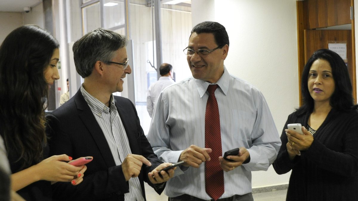 Colegas de trabalho conversam com os celulares na mão