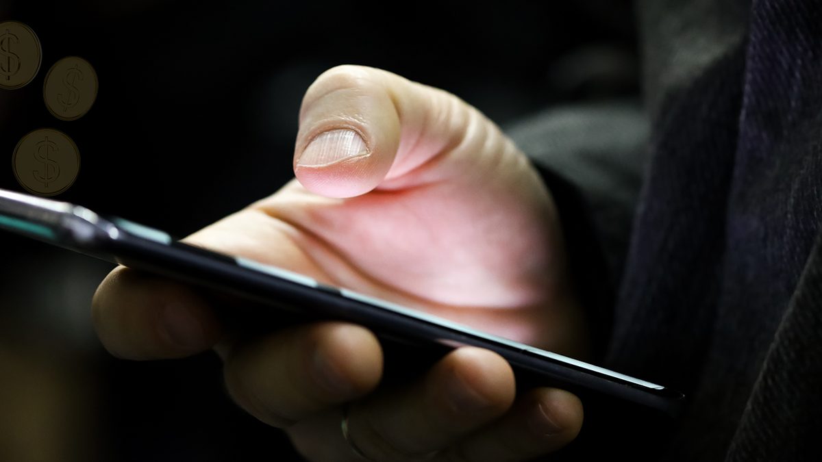 Mão segurando um celular no escuro, imagem usada pelo TRF5 no alerta sobre golpes com RPVs e precatórios