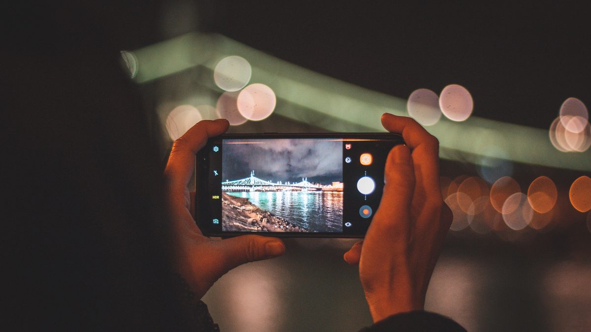Pessoa segura um celular na horizontal à noite, com a tela de câmera ligada