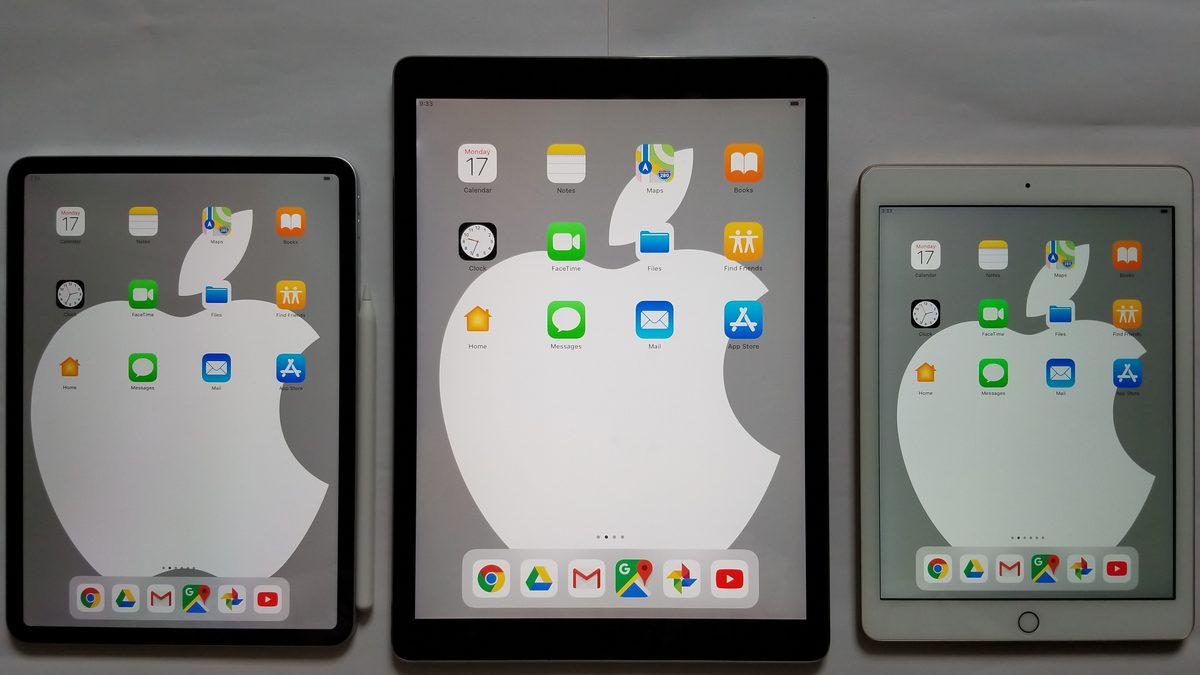 Três iPads de tamanhos diferentes lado a lado sobre fundo cinza, com a tela inicial acesa